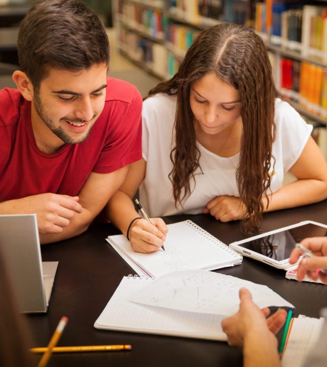 Group of young adults studying together and having a good time in the school library